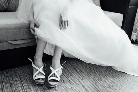 the bride puts on white shoes on feetの写真素材