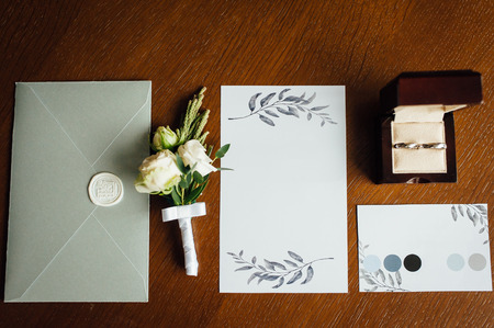 Stylish invitation card with envelope, rings and boutonniere groomの写真素材