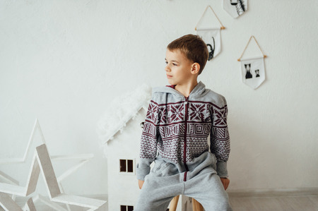 very cute and beautiful baby in pajamas sitting near a white wall.の写真素材