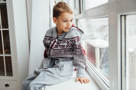 very cute and beautiful baby in pajamas sitting near a window.の写真素材