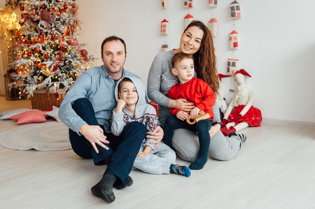 family of four embracing sitting on the floor. Two sons hug their parentsの写真素材