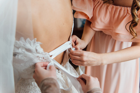 Bridesmaid preparing bride for the wedding day. Wedding conceptの写真素材
