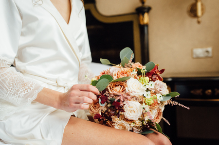 Morning bride. A woman in a white wedding dress holding a bouquet of flowers in her hands.の写真素材