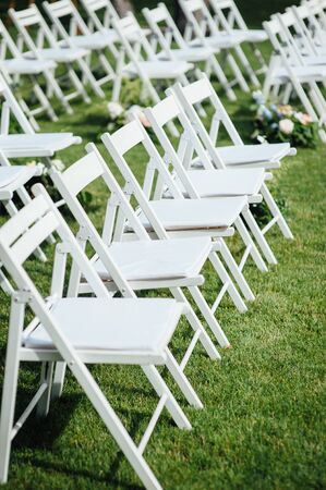 Outgoing wedding ceremony. Decor Studio. white wooden chairs on a green lawn.の写真素材