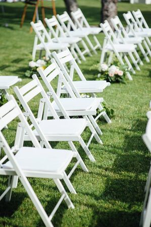 Outgoing wedding ceremony. Decor Studio. white wooden chairs on a green lawn.の写真素材