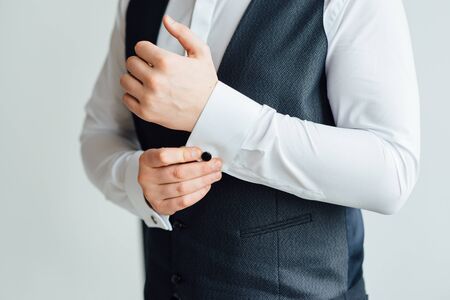 Close-up of a man in a tux fixing his vintage cufflink. groom bow tie cufflinks.