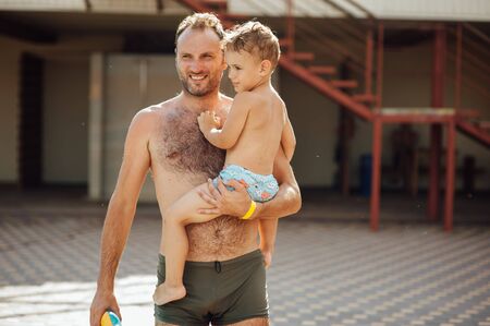 Father and son funny in water pool under sun light at summer day. Leisure and swimming at holidaysの写真素材