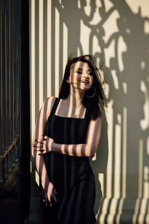 Close-up of a face of a young girl who smiles and a shadow from a metal lattice on her faceの写真素材