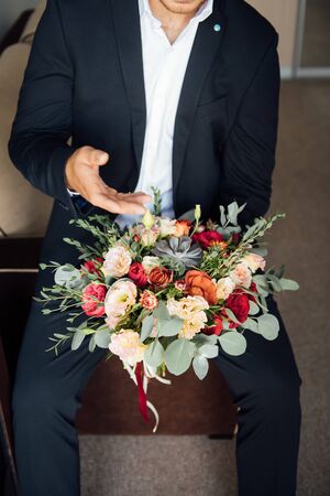the groom waits for the bride and holds in hands a beautiful wedding bouquetの写真素材