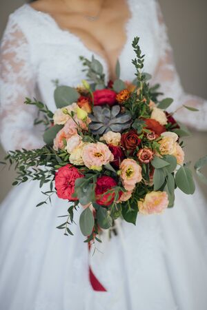 bride in a white dress holding a bouquet of flowers and greeneryの写真素材
