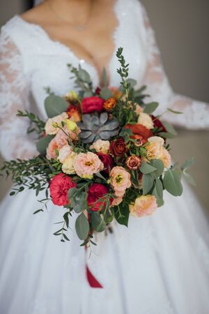 bride in a white dress holding a bouquet of flowers and greeneryの写真素材