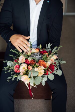 the groom waits for the bride and holds in hands a beautiful wedding bouquetの写真素材