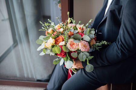 the groom waits for the bride and holds in hands a beautiful wedding bouquetの写真素材
