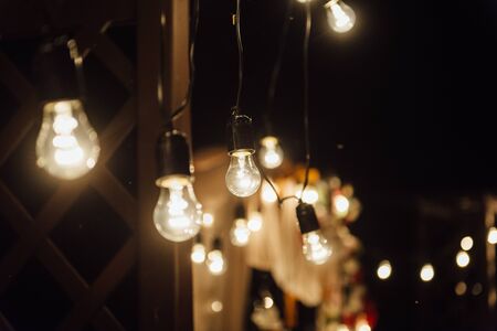 night wedding ceremony. A garland of light bulbs. candles in glass flasks in the evening.の写真素材