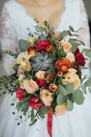 bride in a white dress holding a bouquet of flowers and greeneryの写真素材
