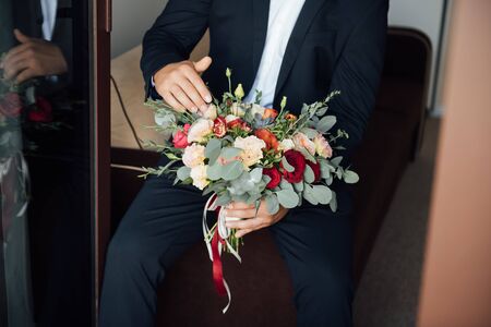 the groom waits for the bride and holds in hands a beautiful wedding bouquetの写真素材