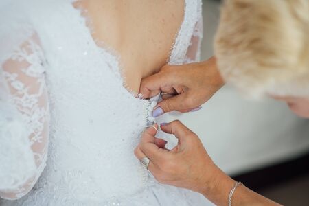 Bridesmaid preparing bride for the wedding day. Best morning. Wedding conceptの写真素材