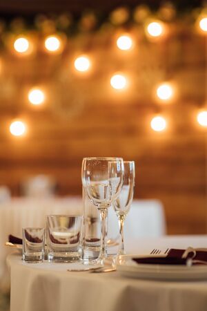 Glasses, flower fork, knife served for dinner in restaurant with cozy interiorの写真素材