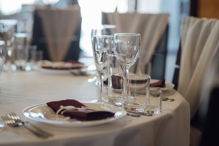 Glasses, flower fork, knife served for dinner in restaurant with cozy interiorの写真素材