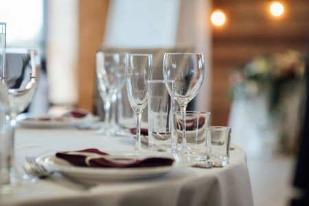 Glasses, flower fork, knife served for dinner in restaurant with cozy interiorの写真素材