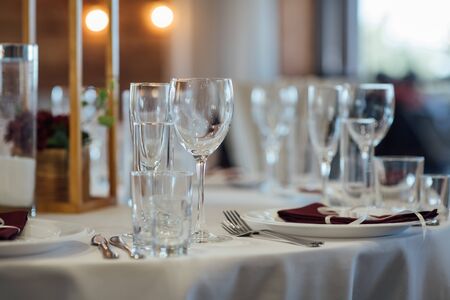 Glasses, flower fork, knife served for dinner in restaurant with cozy interiorの写真素材