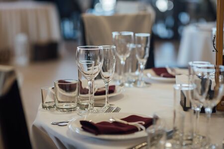 Glasses, flower fork, knife served for dinner in restaurant with cozy interiorの写真素材
