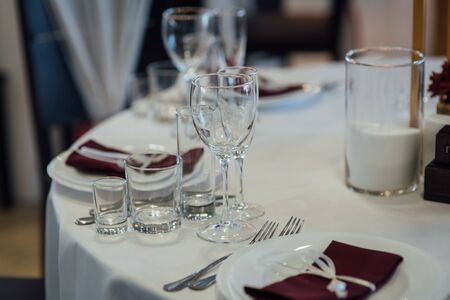 Glasses, flower fork, knife served for dinner in restaurant with cozy interiorの写真素材