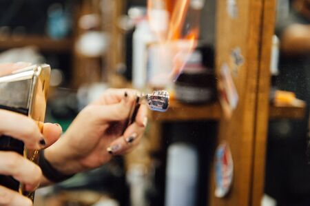 The hands of young barber making haircut to attractive man in barbershopの写真素材