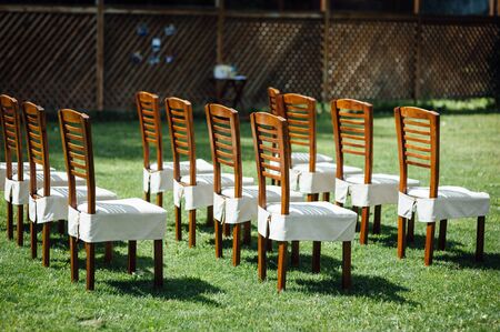 rows of chairs in white capes for guests at a wedding ceremony event outsideの写真素材