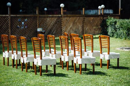 rows of chairs in white capes for guests at a wedding ceremony event outsideの写真素材