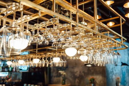 Clean washed and polished glasses hanging over a bar rackの写真素材