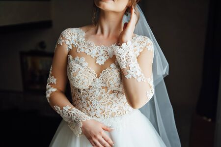 Gorgeous charming sexy bride in white lace dress in hotel room near the door of balcony.の写真素材
