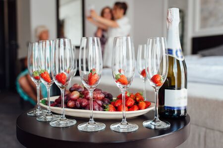 a row of classic glasses with strawberries ready to pour champagne from a bottle. Sparkling wine glasses ready for toastingの写真素材