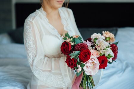 A bride in a white dress is holding a beautiful wedding bouquet.の写真素材