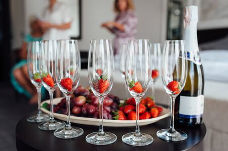 a row of classic glasses with strawberries ready to pour champagne from a bottle. Sparkling wine glasses ready for toastingの写真素材
