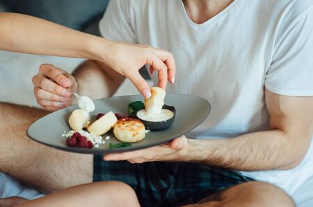 Young beautiful couple eating breakfast in bed.の写真素材