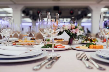 Glasses, flower fork, knife served for dinner in restaurant with cozy interior.の写真素材