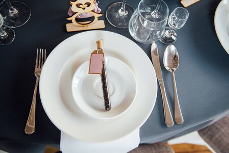 Glasses, flowers, fork, knife served for dinner in restaurant with cozy interior,の写真素材