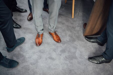 Groom and groomsmen men in blue suits standing in group with closeup of shoes and feet