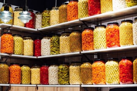 Various jars with Home Canning Fruits and Vegetables jam on glass shelves.の写真素材