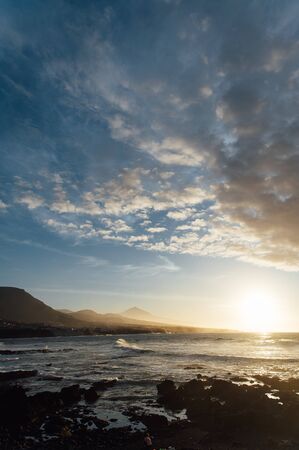 Flight above ocean waves facing beautiful sunset and mountains on horizon.の写真素材