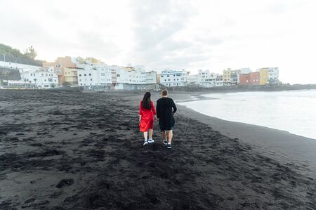 Couple in love walking on the beach near the powerful ocean with the sunset in Puerto de la cruz, Tenerife, Spainの写真素材