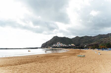 View from the height of the golden sand, palm trees, sun loungers, unrecognizable people on the beach Las Teresitas, Tenerife, Canaries, Spain. cloudy weatherの写真素材