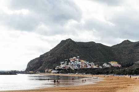 View from the height of the golden sand, palm trees, sun loungers, unrecognizable people on the beach Las Teresitas, Tenerife, Canaries, Spain. cloudy weatherの写真素材