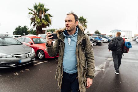 A tourist with a heavy backpack in the parking lot is looking for a car rental companyの写真素材