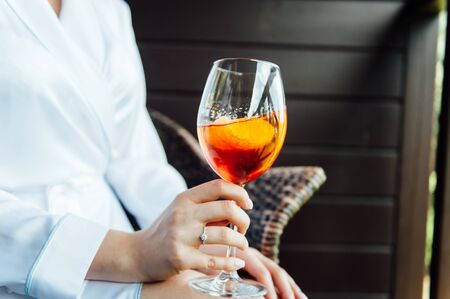 sexy woman holding a glass with aperol cocktail and smiling in the sunの写真素材