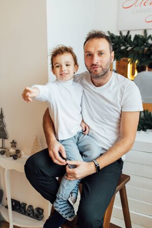 happy father hugs his sons. Photo taken in an apartment with a Christmas treeの写真素材