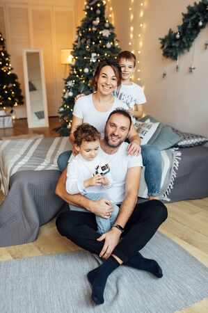 family of four embracing sitting on the floor. Two sons hug their parentsの写真素材