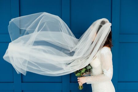 gorgeous bride with transparent veil on a background of blue wall.の写真素材