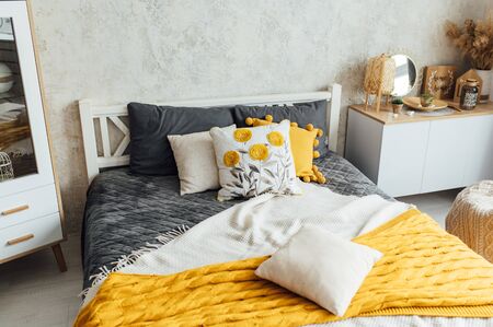 Comfortable, big, wooden bed with linen, pillows and blanket, nightstand beside and round mirror.の写真素材